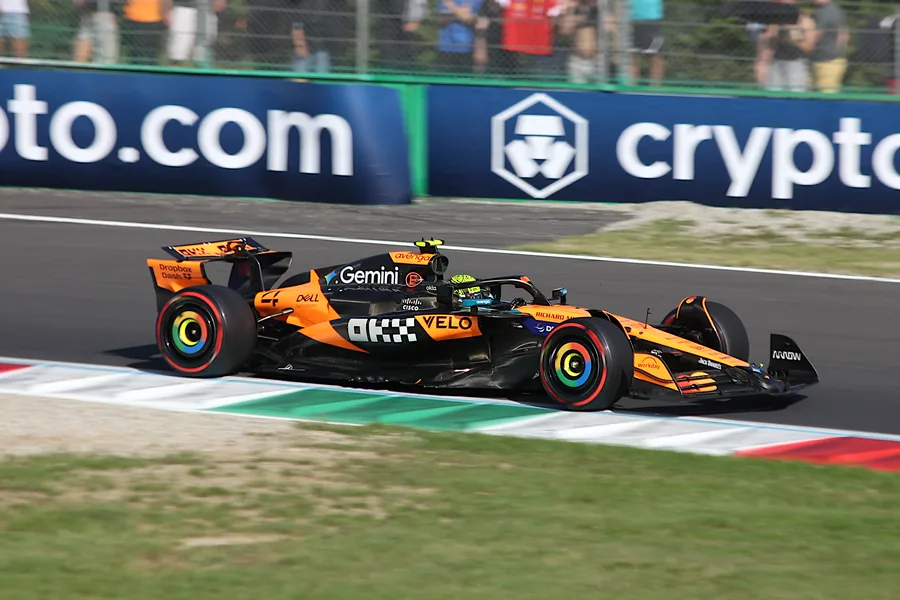 A McLaren running over the green, white and red kerb on the exit of a Monza chicane in 2025
