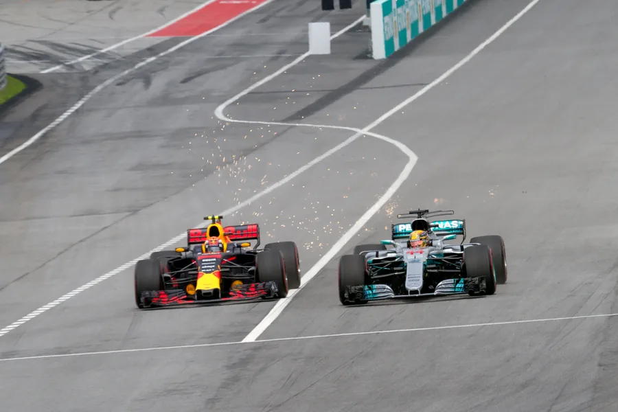 Max Verstappen’s Red Bull and Lewis Hamilton’s Mercedes running side by side on track at Sepang, sparks flying from both cars